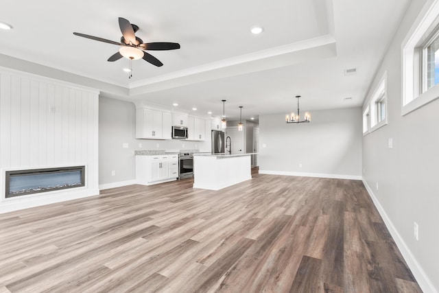 1160 Waterloo St, Troy, OH 45373 - unfurnished living room featuring ceiling fan, a large fireplace, light wood-style floors, a raised ceiling, and recessed lighting