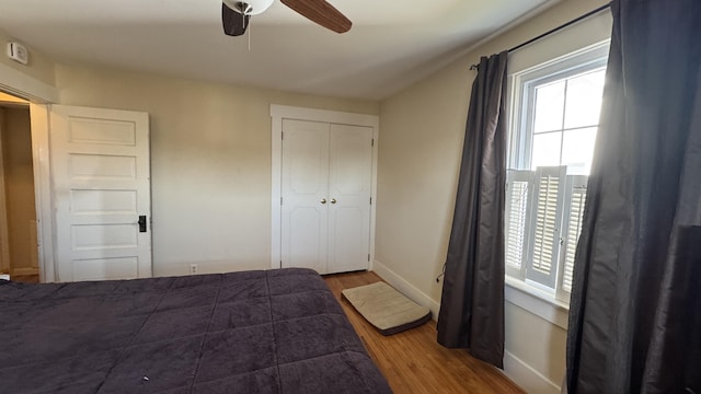 bedroom with a ceiling fan, a closet, baseboards, and wood finished floors