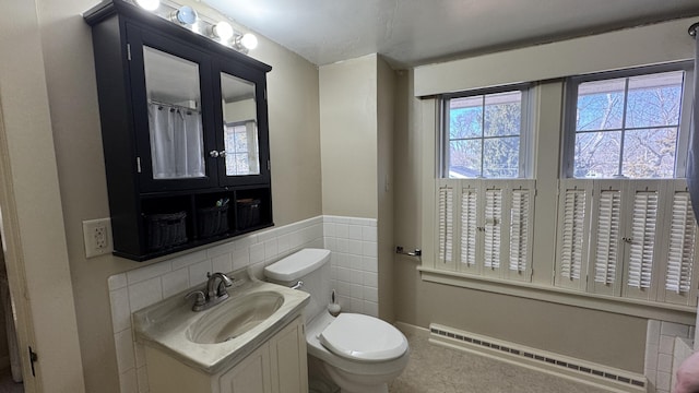 bathroom featuring toilet, a wainscoted wall, a baseboard radiator, vanity, and tile walls