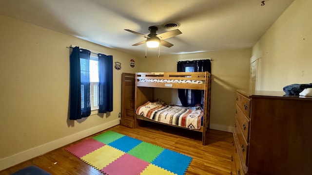 bedroom featuring visible vents, ceiling fan, baseboards, and wood finished floors