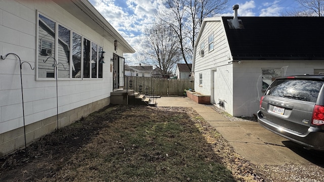 view of property exterior with fence, concrete block siding, and a gambrel roof