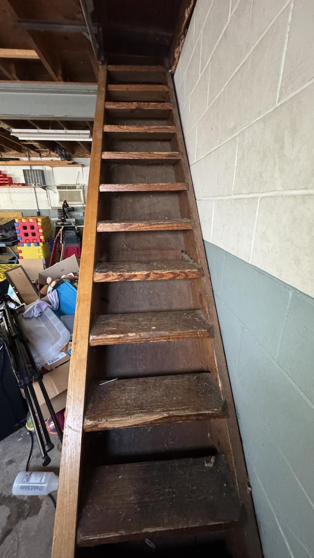 staircase featuring concrete flooring and concrete block wall