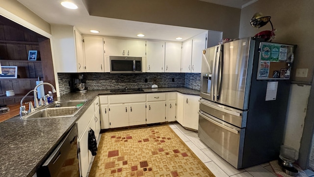 kitchen with dark countertops, decorative backsplash, white cabinetry, a sink, and black appliances