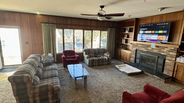 living room with ceiling fan, wooden walls, carpet floors, a fireplace, and built in features