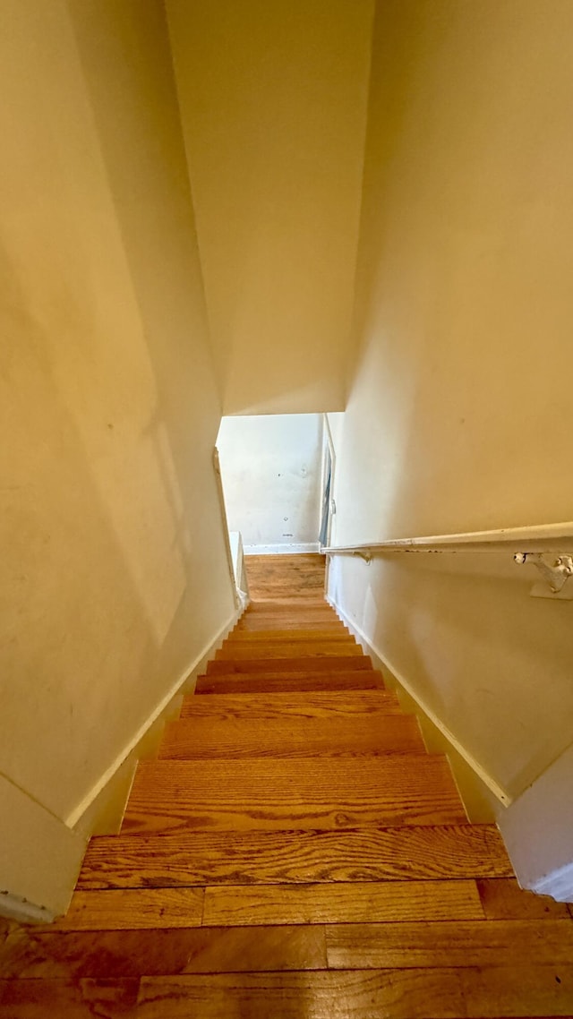 stairs with a towering ceiling and wood finished floors