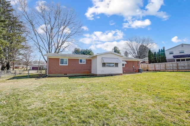 back of property with crawl space, brick siding, a lawn, and a fenced backyard