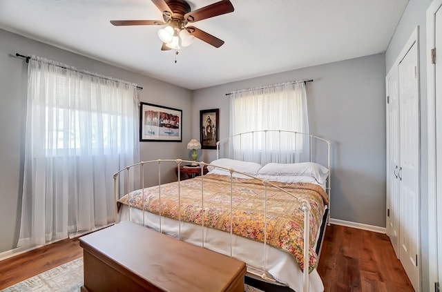 bedroom featuring a ceiling fan, a closet, baseboards, and wood finished floors