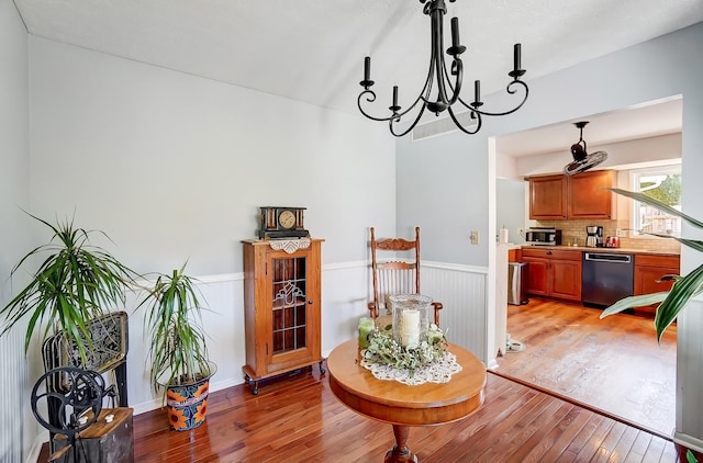 dining room featuring a wainscoted wall, light wood finished floors, visible vents, and a notable chandelier