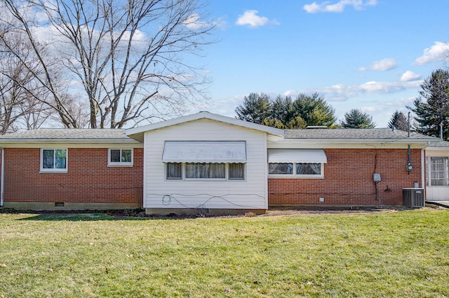 rear view of property featuring crawl space, brick siding, and a lawn