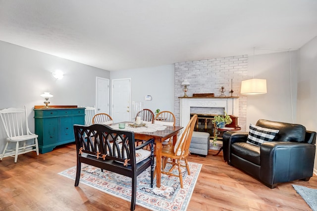 dining room with light wood finished floors and a brick fireplace