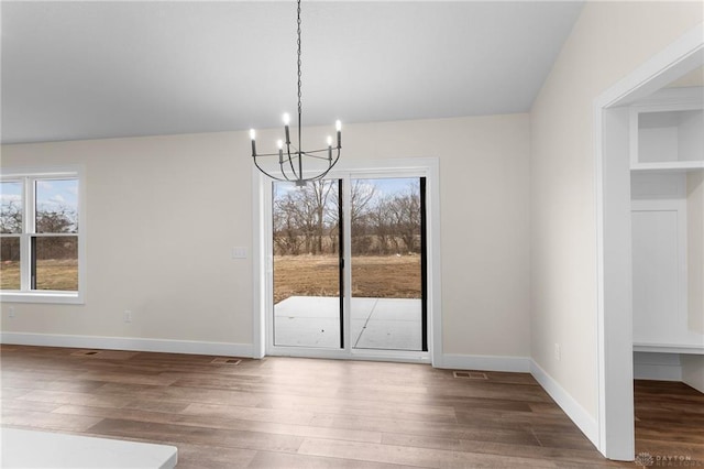 unfurnished dining area with dark hardwood / wood-style flooring and a notable chandelier