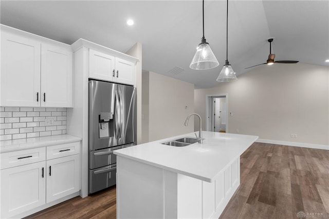 kitchen featuring decorative backsplash, an island with sink, stainless steel fridge with ice dispenser, a sink, and vaulted ceiling