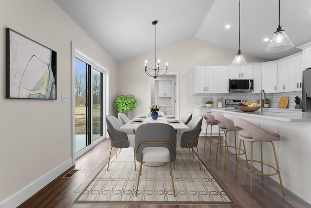 dining space with dark wood-style flooring, a notable chandelier, baseboards, lofted ceiling, and visible vents