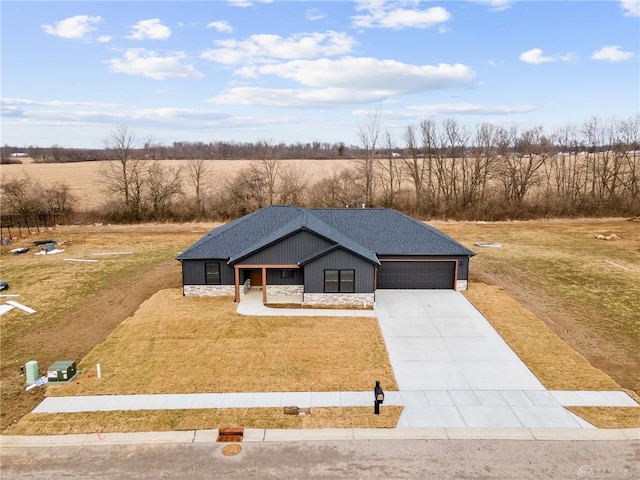 view of front of property featuring a rural view, a garage, a front yard, and a porch