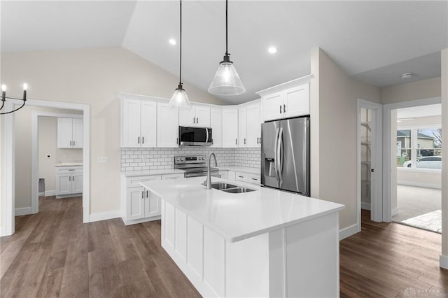 kitchen with pendant lighting, sink, white cabinetry, stainless steel appliances, and a center island with sink