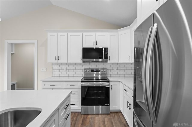 kitchen with lofted ceiling, white cabinetry, backsplash, stainless steel appliances, and dark hardwood / wood-style floors