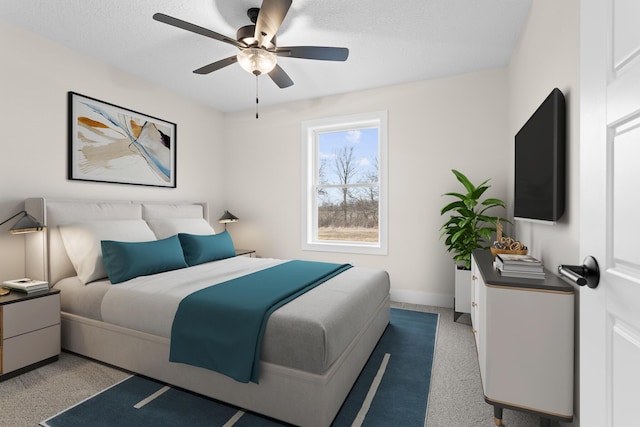 bedroom with baseboards, a ceiling fan, a textured ceiling, and light colored carpet
