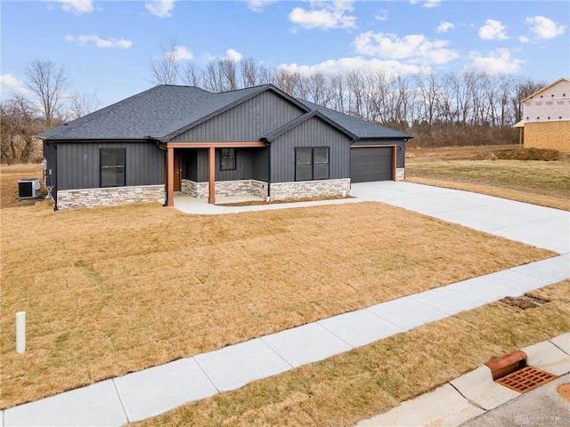 view of front of house with a garage, a front yard, central AC unit, and covered porch