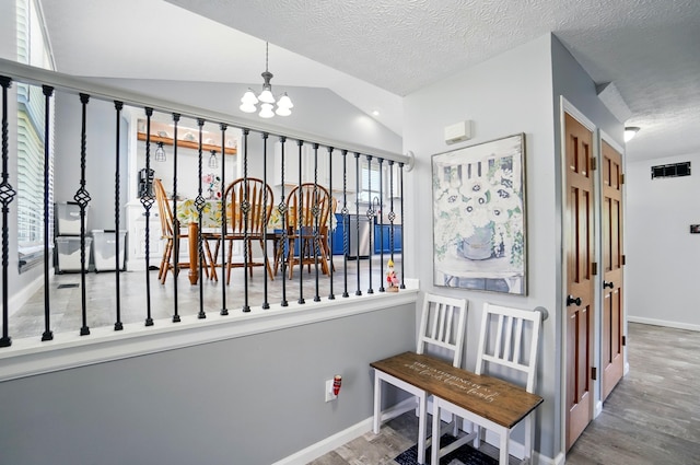 1627 Metcalfe Ave, Columbus, OH 43207 - hall with wood finished floors, a chandelier, lofted ceiling, and a textured ceiling