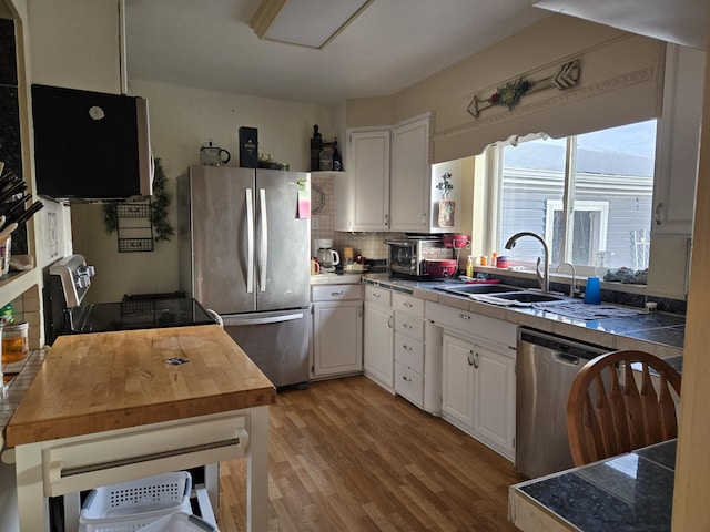 kitchen with white cabinetry, tasteful backsplash, a sink, and stainless steel appliances