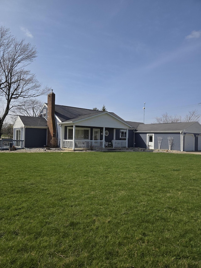 view of front of home with covered porch, a garage, a front lawn, and a chimney