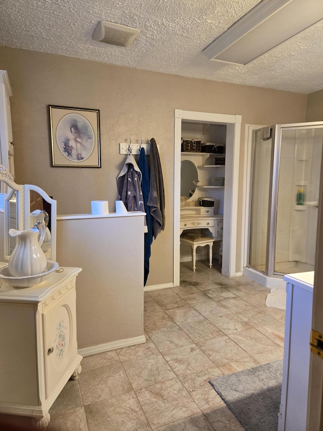 full bath featuring a shower stall, baseboards, and a textured ceiling