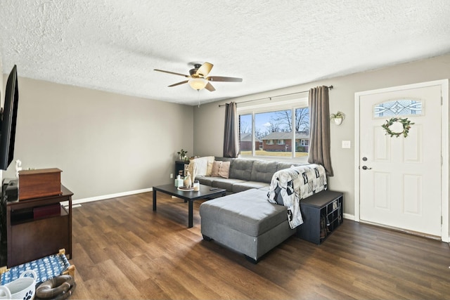 living area with a textured ceiling, baseboards, ceiling fan, and dark wood-style flooring