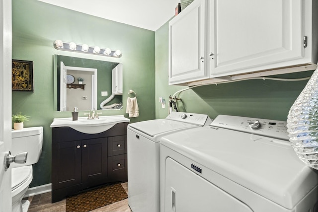 clothes washing area with independent washer and dryer, a sink, wood finished floors, baseboards, and laundry area