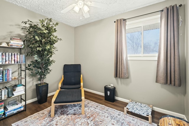 living area with ceiling fan, wood finished floors, baseboards, and a textured ceiling