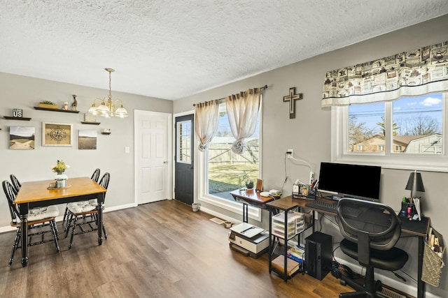 dining area featuring a textured ceiling, wood finished floors, baseboards, and a chandelier