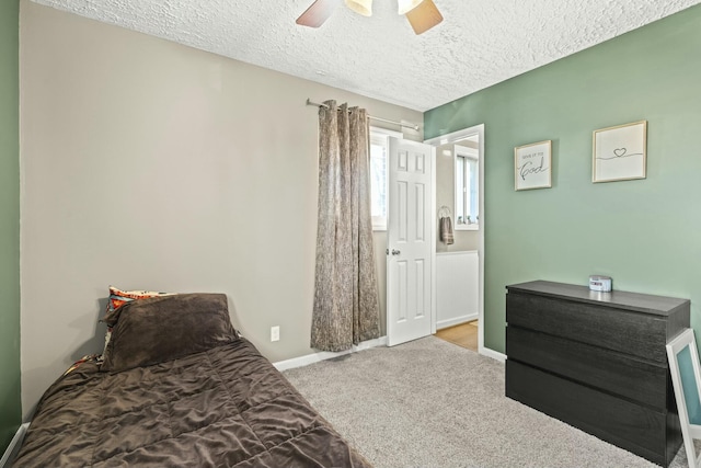 carpeted bedroom with a ceiling fan, baseboards, and a textured ceiling