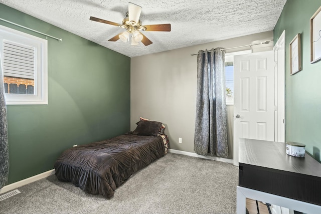 bedroom with visible vents, baseboards, ceiling fan, carpet flooring, and a textured ceiling