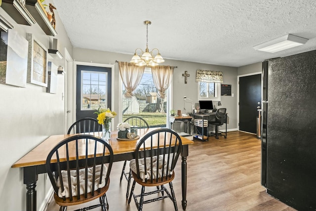 dining room with an inviting chandelier, wood finished floors, baseboards, and a textured ceiling