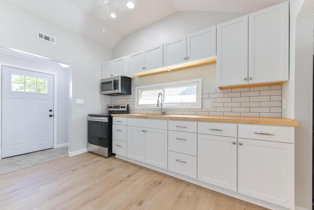 127 Brads Way, Russells Point, OH 43348 - kitchen with appliances with stainless steel finishes, wooden counters, light wood-style flooring, backsplash, and vaulted ceiling