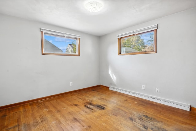 empty room featuring baseboards, hardwood / wood-style floors, and baseboard heating