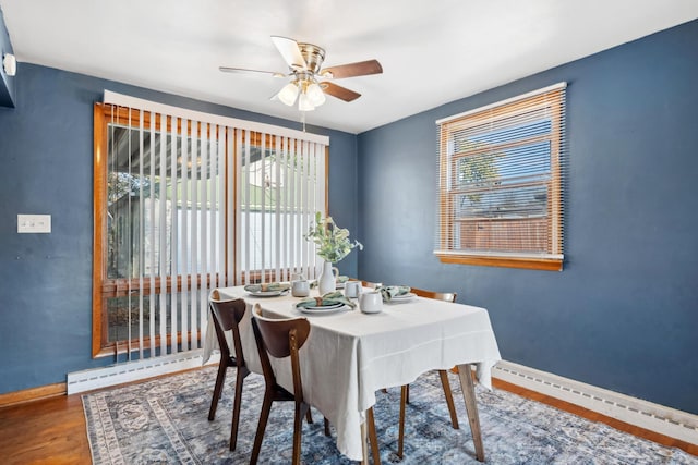 dining space featuring ceiling fan, a baseboard radiator, wood finished floors, and baseboards