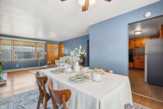 dining space with a ceiling fan and wood finished floors