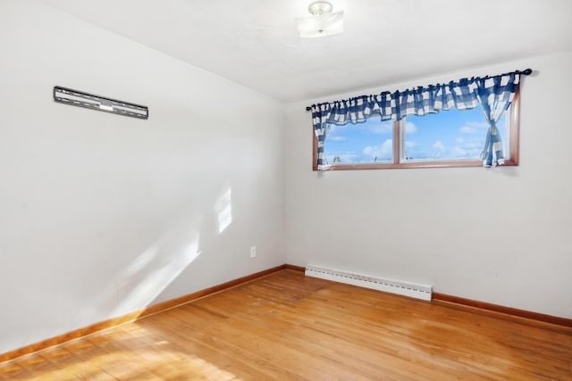 spare room with baseboards, baseboard heating, and wood finished floors