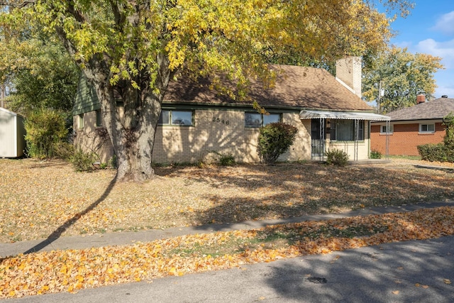 view of front of house with brick siding and a chimney