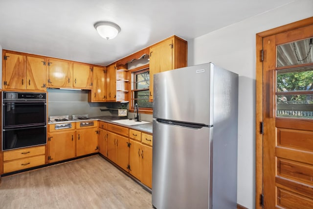 kitchen featuring plenty of natural light, brown cabinets, a sink, and freestanding refrigerator