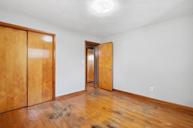 unfurnished bedroom with light wood-style floors, a closet, and baseboards