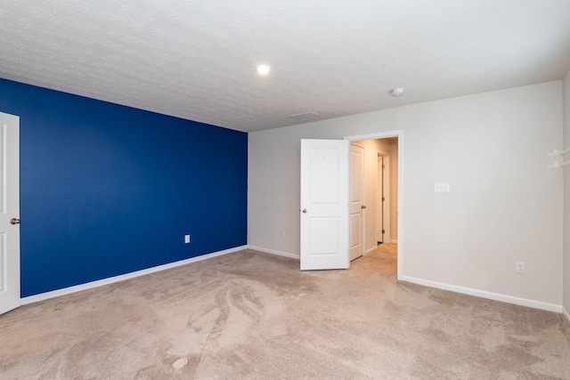 carpeted spare room featuring visible vents, baseboards, and a textured ceiling