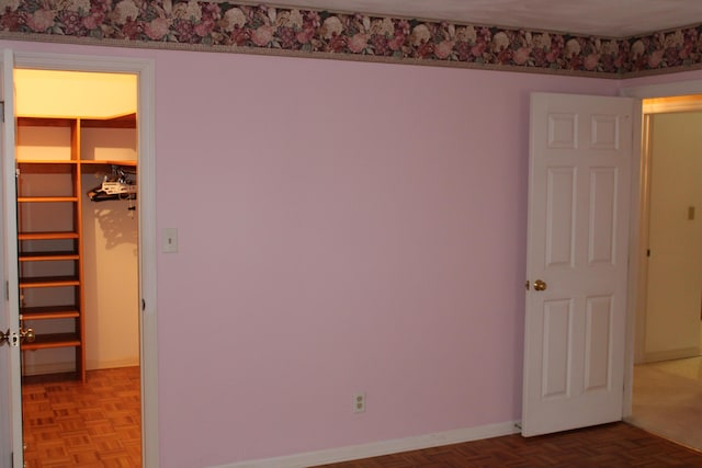 unfurnished bedroom with a spacious closet, a closet, and light parquet flooring