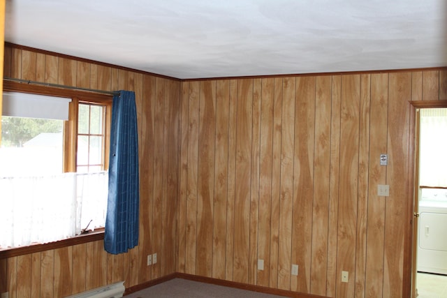 carpeted spare room featuring a baseboard radiator, washer / clothes dryer, and wood walls