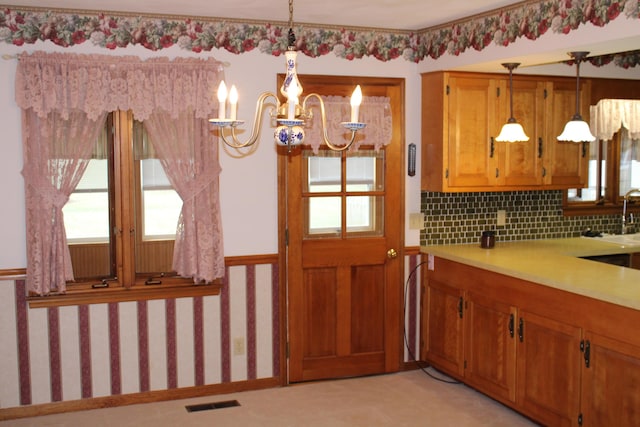 kitchen featuring pendant lighting, sink, tasteful backsplash, and an inviting chandelier