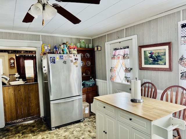 kitchen with ceiling fan, wood counters, crown molding, and stainless steel refrigerator