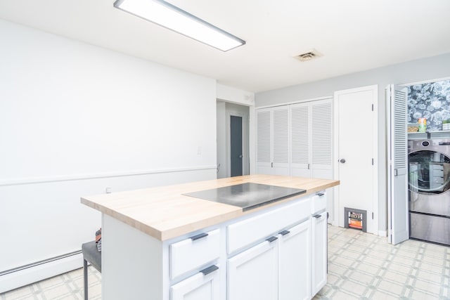 kitchen featuring light floors, washer / dryer, white cabinetry, baseboard heating, and butcher block counters