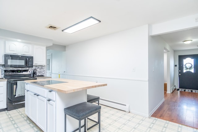 kitchen featuring black appliances, white cabinets, a kitchen bar, baseboard heating, and butcher block counters