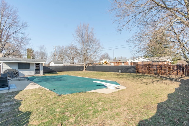 view of swimming pool with an outbuilding, a patio, a fenced backyard, a yard, and a diving board