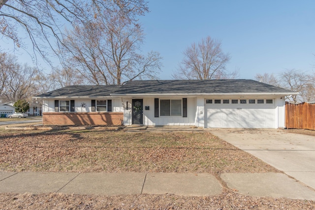 ranch-style home featuring fence, board and batten siding, concrete driveway, a garage, and brick siding